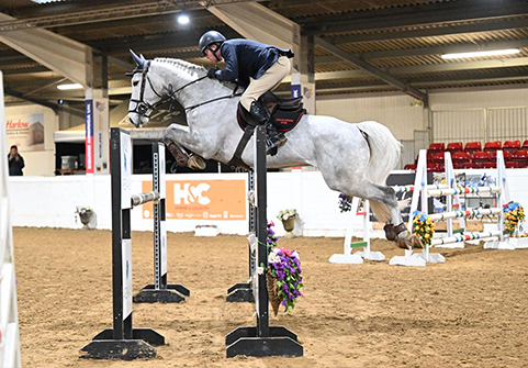 Horse and rider clearing a fence at an indoor competition